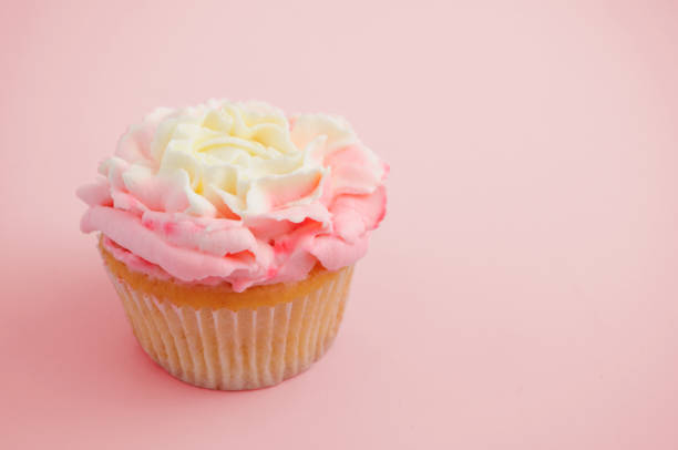 istock Cupcake with pink cream rose flower on pink background. 870113370