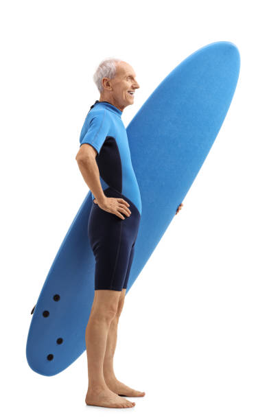 istock Senior in a wetsuit holding a surfboard and waiting in line 870113532