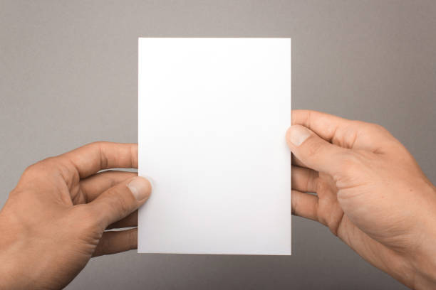 istock Blank postcard in hands on a gray background. Leaflet A6 mockup 870122976