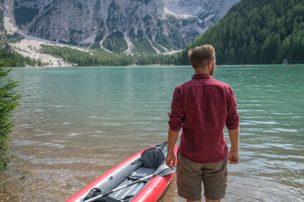 istock Ready to go, young man with canoe at mountain lake 870136958