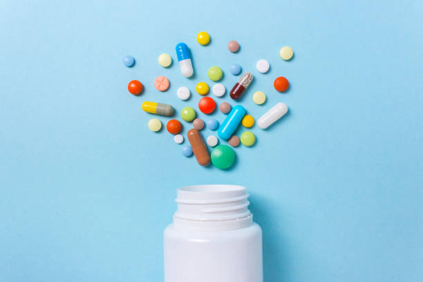 istock Assorted pharmaceutical medicine pills, tablets and capsules and bottle on blue background 870137292