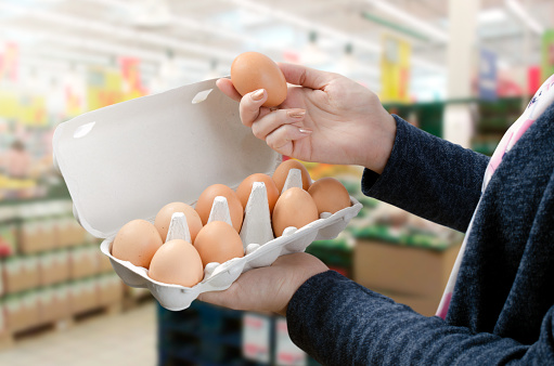 Woman buys eggs in the supermarket. Egg store supermarket price expensive grocery shop concept