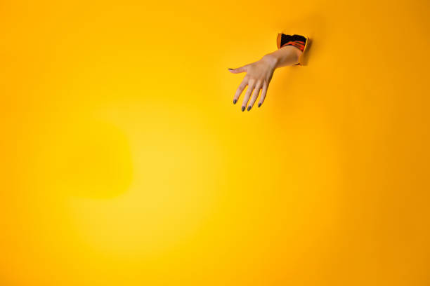 istock Woman hand making sign through a hole in paper 870142108