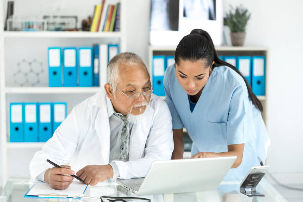 Medical specialists using laptop in cabinet
