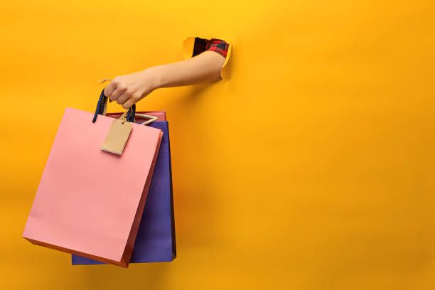 mano femminile che tiene borse della spesa luminose - modella negozio foto e immagini stock