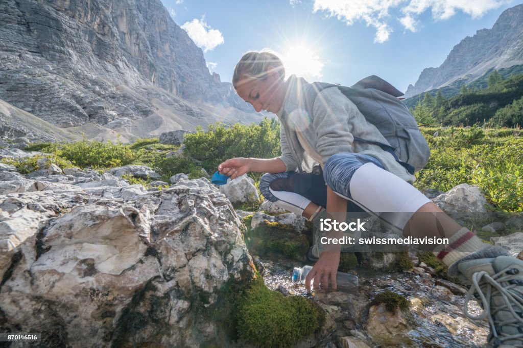 Uzun yürüyüşe çıkan kimse kadın dolgu kabak gelen taze akış dağ yolu, Dolomites, İtalya - Royalty-free Doldurmak Stok görsel