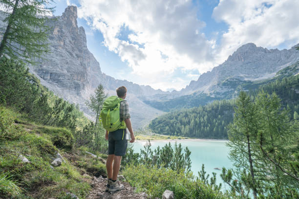 Hiking man contemplating Alpine lake in Italy Young man contemplating nature by the mountain lake in Alto Adige in South Tyrol region, Italy trentino south tyrol stock pictures, royalty-free photos & images