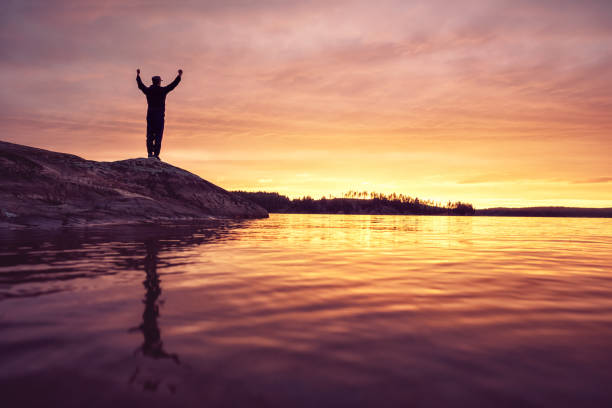Man standing on a rock formation at a lake