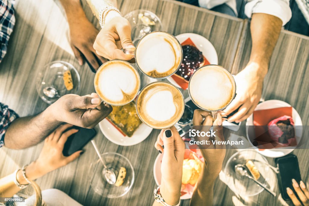 Friends group drinking cappuccino at coffee bar restaurant - People hands toasting at fashion cafeteria with upper view point - Winter drinks concept with men and women at cafe - Warm vintage filter Breakfast Stock Photo