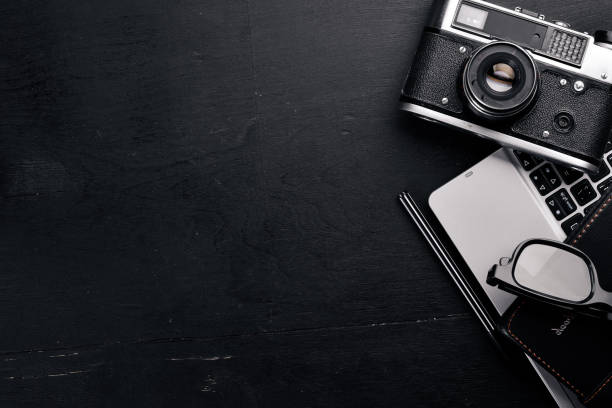istock Office work space with camera, notebook, eyepieces, and pen. On a wooden surface. Top view. Free space for your text. 870150740
