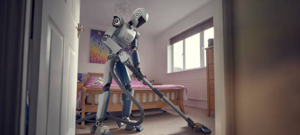 Robot Doing Household Cleaning With Vacuum Cleaner A conceptual images of a generic, blue and white robot holding a vacuum cleaner doing household cleaning chores in bedroom, viewed from a low angle through an open doorway. Concepts include home automation, technology and innovation.  robot cleaning stock pictures, royalty-free photos & images