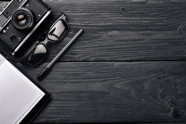 istock Office work space with camera, notebook, eyepieces, and pen. On a wooden surface. Top view. Free space for your text. 870153694