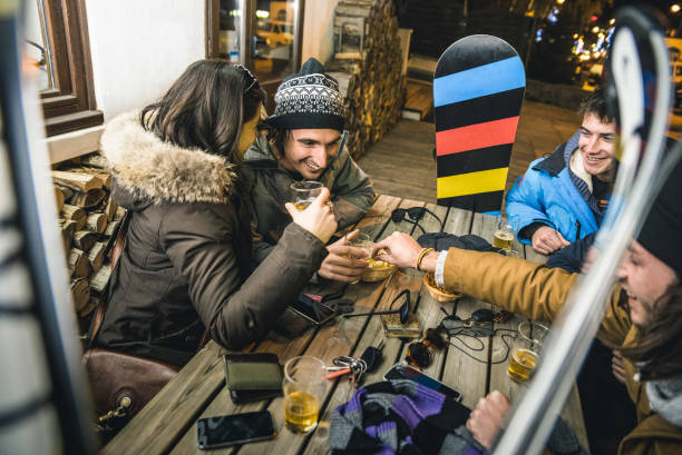 amici felici che bevono birra e mangiano patatine allo sci apres - concetto di amicizia con persone allegre che si divertono al bar restaurant resort con attrezzatura da neve - immagine ad alto iso con profondità di campo bassa - snowboarding friendship snow winter foto e immagini stock