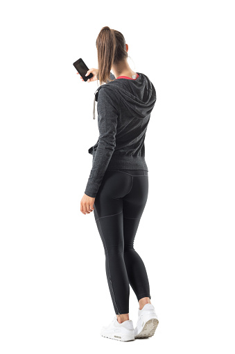 Back view of young sporty fit woman taking photo with smartphone. Full body length portrait isolated on white background.