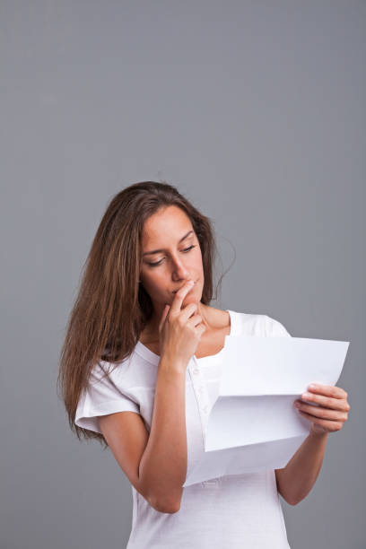 woman thinking about that letter woman mumbling about a sheet document or letter she's holding in her hand human body lice stock pictures, royalty-free photos & images