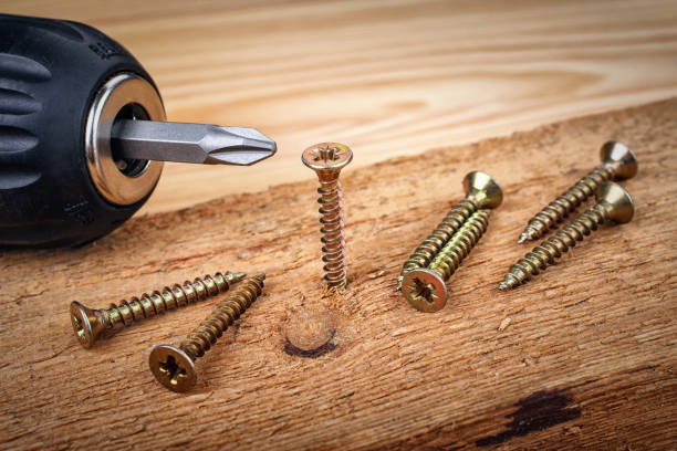 istock cordless drill and large screws on a wood background 870161848