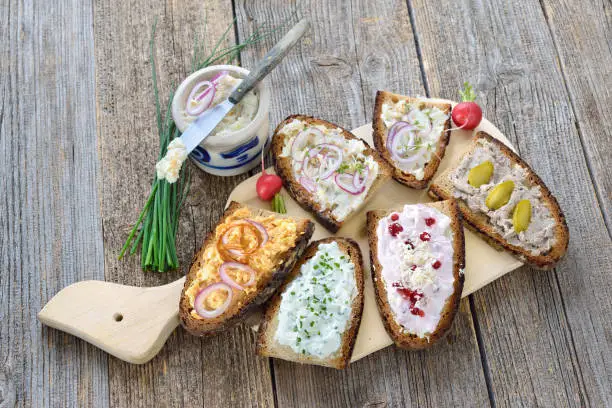 Hearty snack with different kinds of spreads on farmhouse bread served on an old wooden table