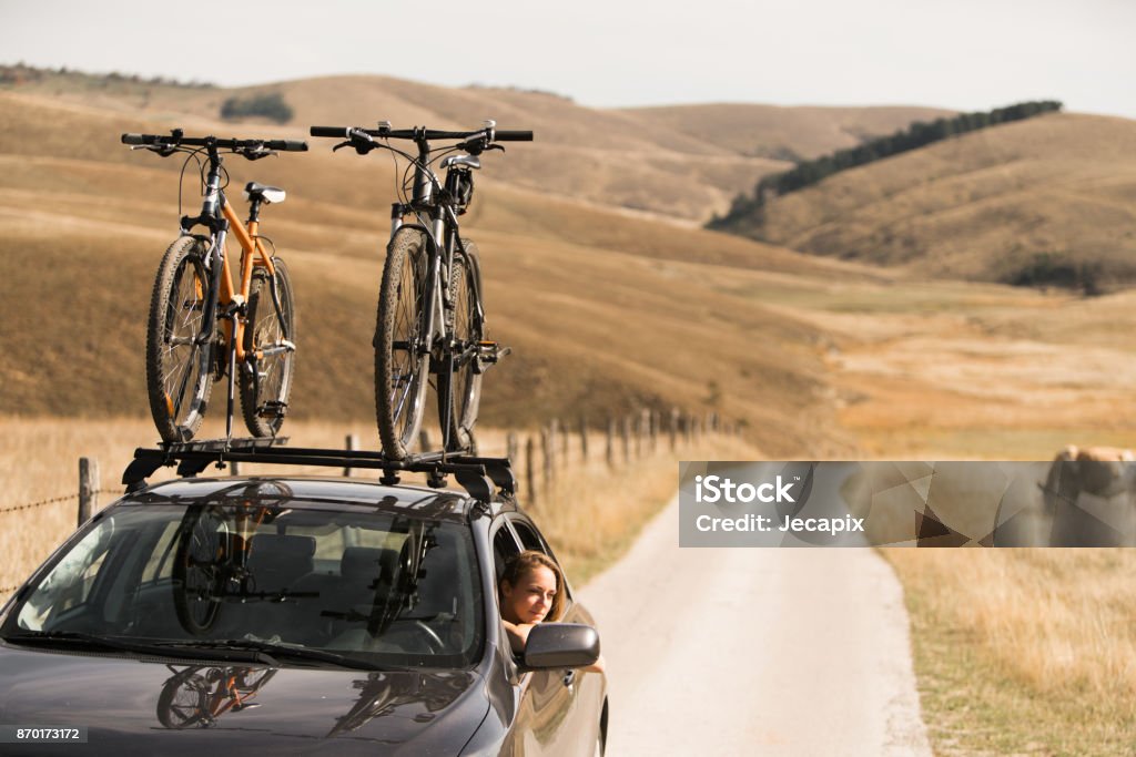 Adveture time on roadtrip Young woman making a break on her roadtrip and looking on the beautiful landscape through the car window Bicycle Stock Photo