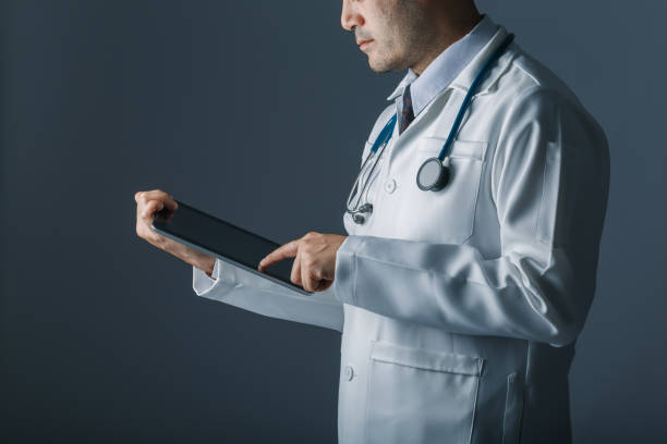 istock Asian smart doctor holding and touch tablet computer with hand. Surgeon has stethoscopes. concept of medical, technology, information and big data. 870188872