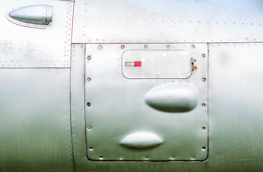 Old aircraft fuselage close up. Door handle and rivets.