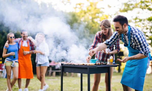 молодые люди жарят на открытом воздухе - sausage barbecue grill barbecue cooking стоковые фото и изображения