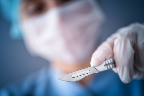 Surgeon doctor with a scalpel Surgeon scalpel, Hand, Lancet, Blue on background scalpel photos stock pictures, royalty-free photos & images