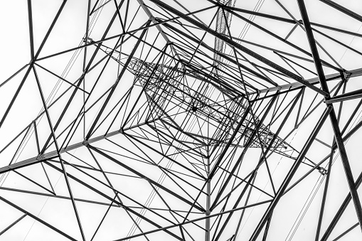 tall power line pylon silhouette against sky looking up