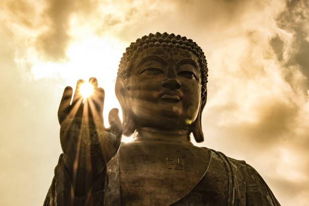 soleil qui brille à travers de tian tan buddha géant sur la colline à hong kong - bouddha photos et images de collection