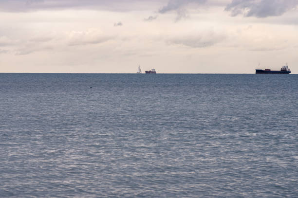 zwei schiffe und ein segel boot auf dem meer am horizont - industrial ship audio stock-fotos und bilder