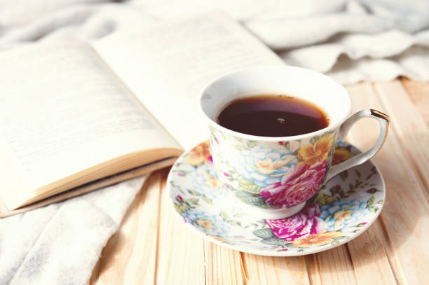 istock Cozy home still life: cup of hot coffee or tea and opened book with warm plaid 870223268