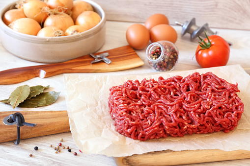 Raw minced meat, eggs, and detail of meat grinder