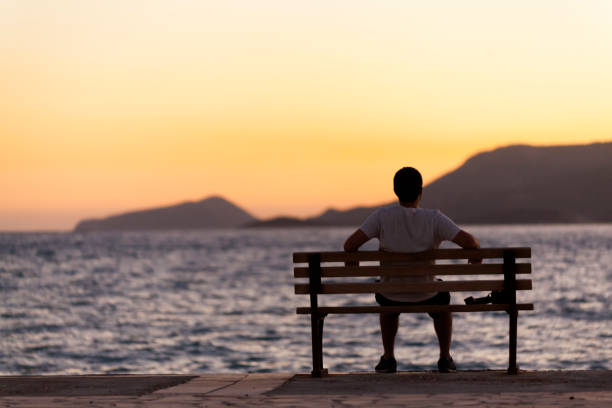 istock Lonely Man Sitting Watching the Sunset 870233316