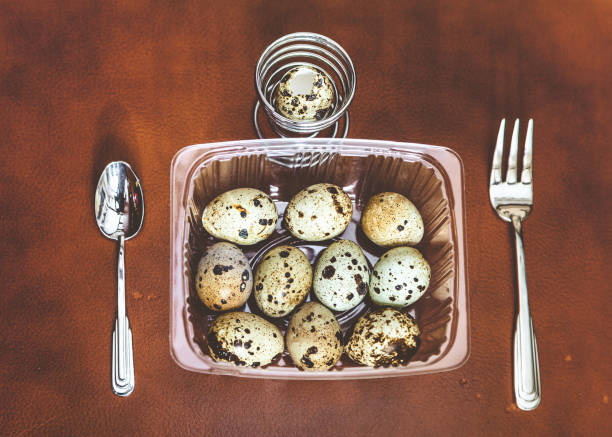 istock Quail eggs lie in transparent box. Near fork, spoon 870239920
