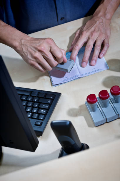 us border security, homeland security, pass prüfstation für einwanderung - customs official examining emigration and immigration document stock-fotos und bilder