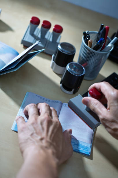 us border security, homeland security, pass prüfstation für einwanderung - customs official examining emigration and immigration document stock-fotos und bilder