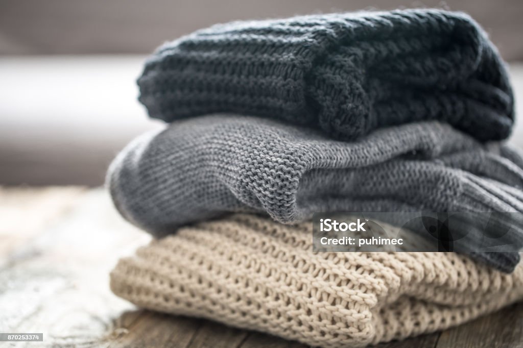 stack of cozy knitted sweaters stack of cozy knitted sweaters on wooden background. Autumn-winter concept Cardigan Sweater Stock Photo