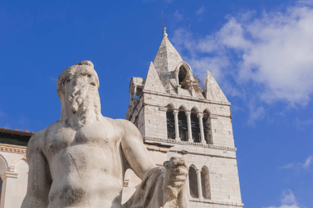 The 16th century marble statue of the Giant (Andrea Doria) with the cathedral tower in the background in Carrara, Tuscany, Italy