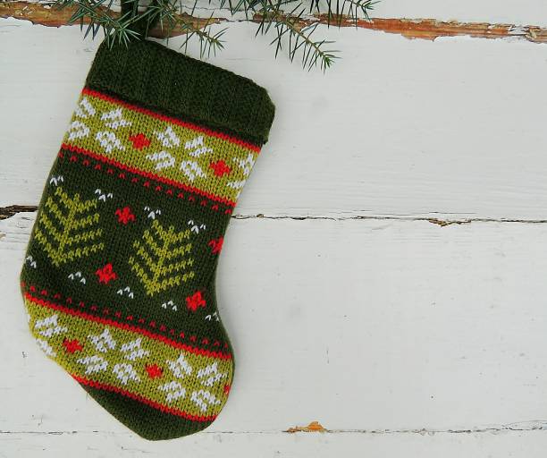 istock Christmas knitted mini sock with winter ornament on vintage white background. 870277828