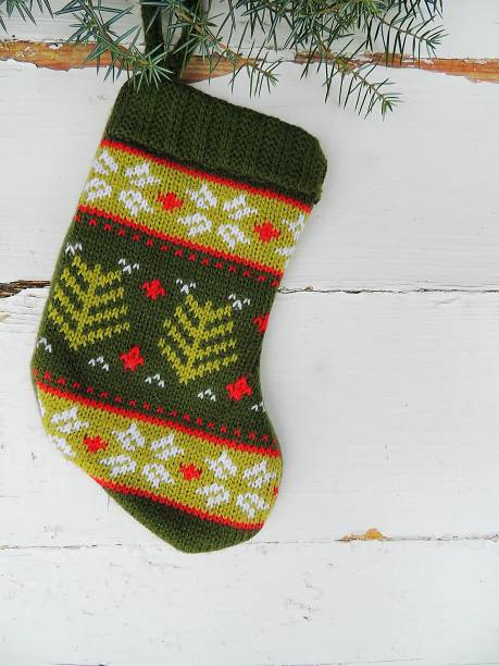 istock Christmas knitted mini sock with winter ornament on vintage white background. 870278054