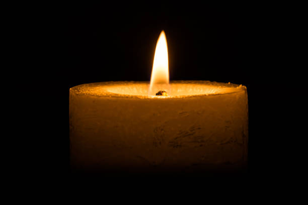 istock candle burns at dusk, a candle fire on a black background 870283812