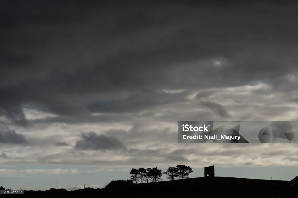 Silhouette of derelict tower and trees, against a dramatic sky Silhouette of derelict tower (either a former windmill or castle) and trees, against a dramatic sky.  Killough, County Down, Northern Ireland. Castle Stock Photo