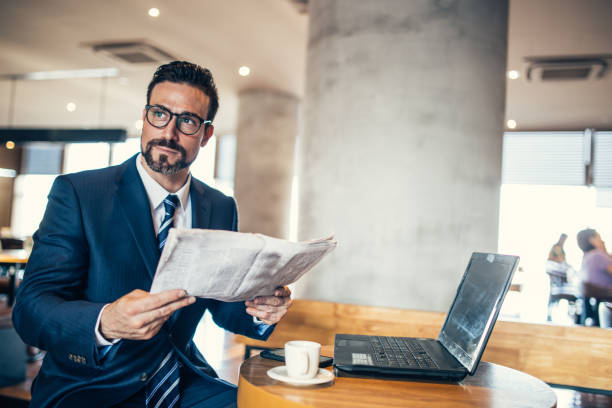 istock Businessman reading newspaper in cafe 870289968