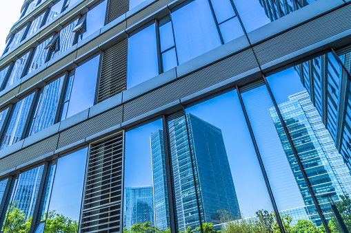 Window of a big office building. Blue sky and fluffy white clouds reflected in the windows of modern skyscraper