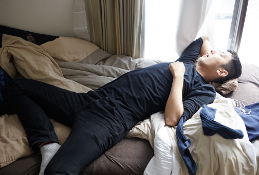Young Japanese man taking a nap on a messy bed