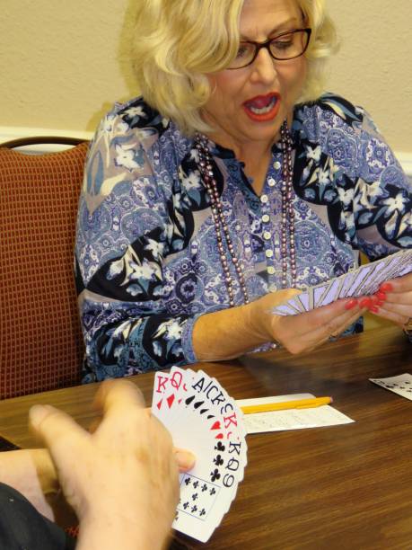 istock older woman playing cards, surprised 870368018