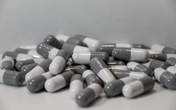 un sacco di capsule di pillole ingoiate su sfondo bianco contatore - pilled foto e immagini stock