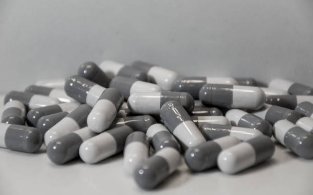 lots of pills capsules pilled up on counter white background - pilled imagens e fotografias de stock