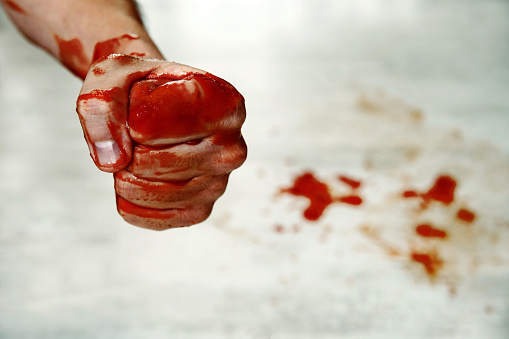 Fists with blood. Fighter. Fist blood closeup on the background of the drops of blood on the floor. Fighter fighter shows a bloody hand folded in a fist