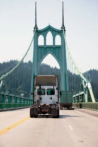 Photo of Big rig semi truck tractor driving by awesome St Johns bridge