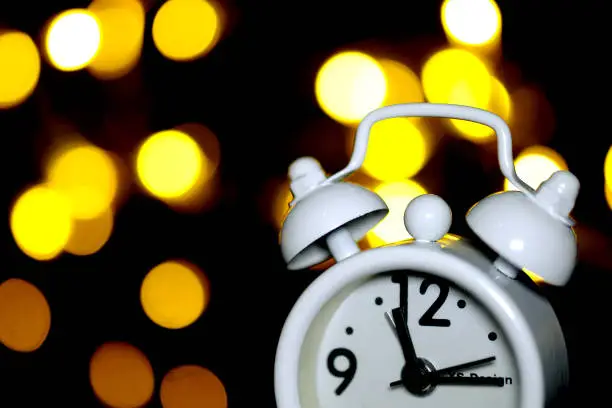 a white clock with some bokeh light background